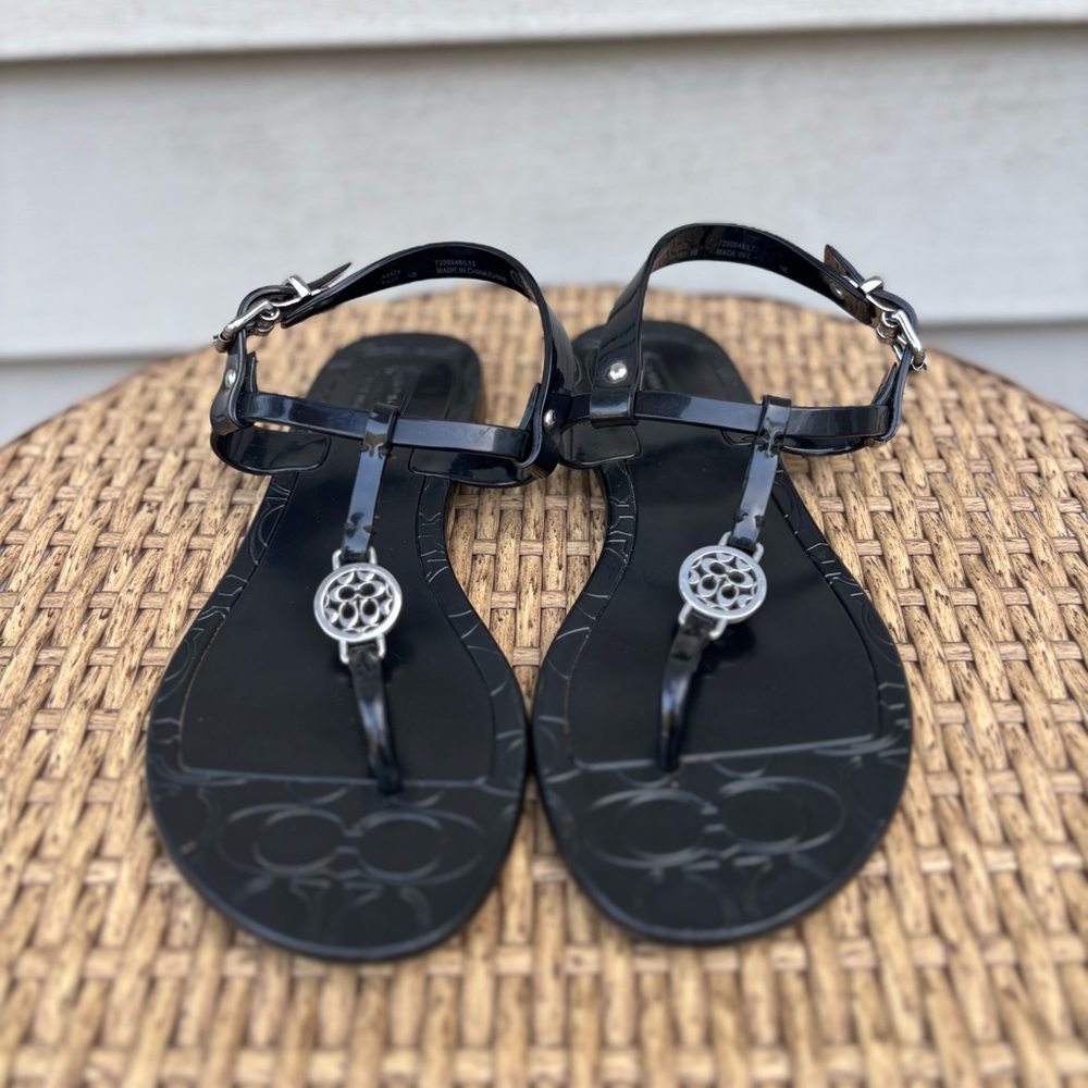 Coach- Women’s Black Sandals With Embossed Logo and Adjustable Buckle Closure.
